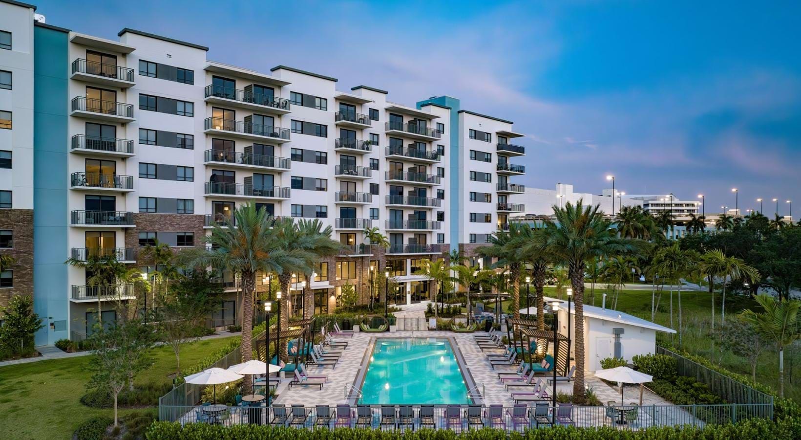 Resort-style swimming pool a building with palm trees and a blue sky
